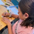 Ein Mädchen paust die Braillepunkte auf den Schlüsselanhänger.