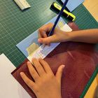 Kinderhände pausen Brailleschrift auf eine hellblaue Karte.