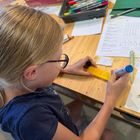Mädchen am Schreiben der Brailleschrift mit blauem Dot-Pen auf gelben Schlüsselanhänger.