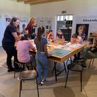 Gruppe mit Kindern am Basteln und zwei erwachsenen Personen.